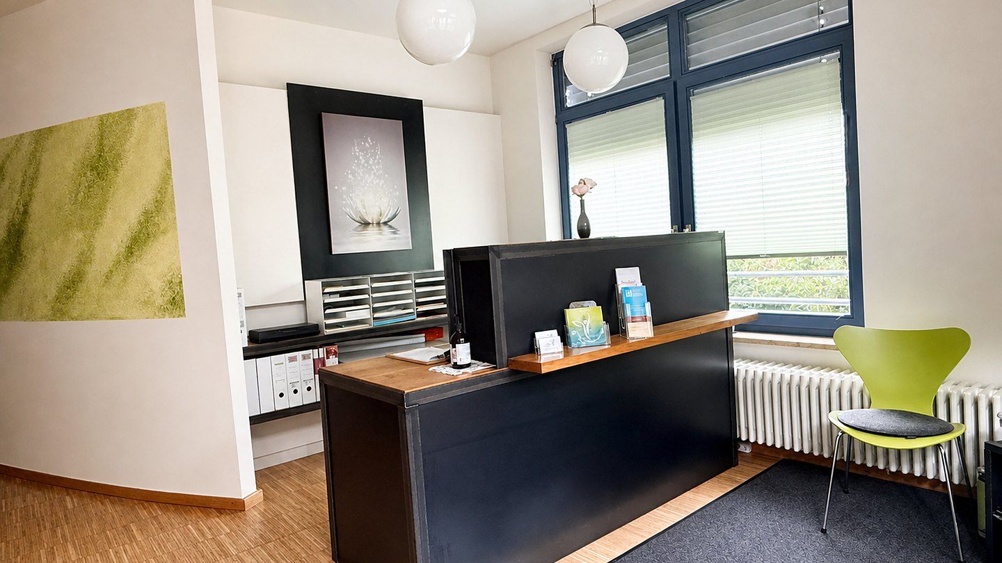 Heller Empfangsbereich der Heilpraxis Bad Heilbrunn mit Rezeption und Sitzplatz